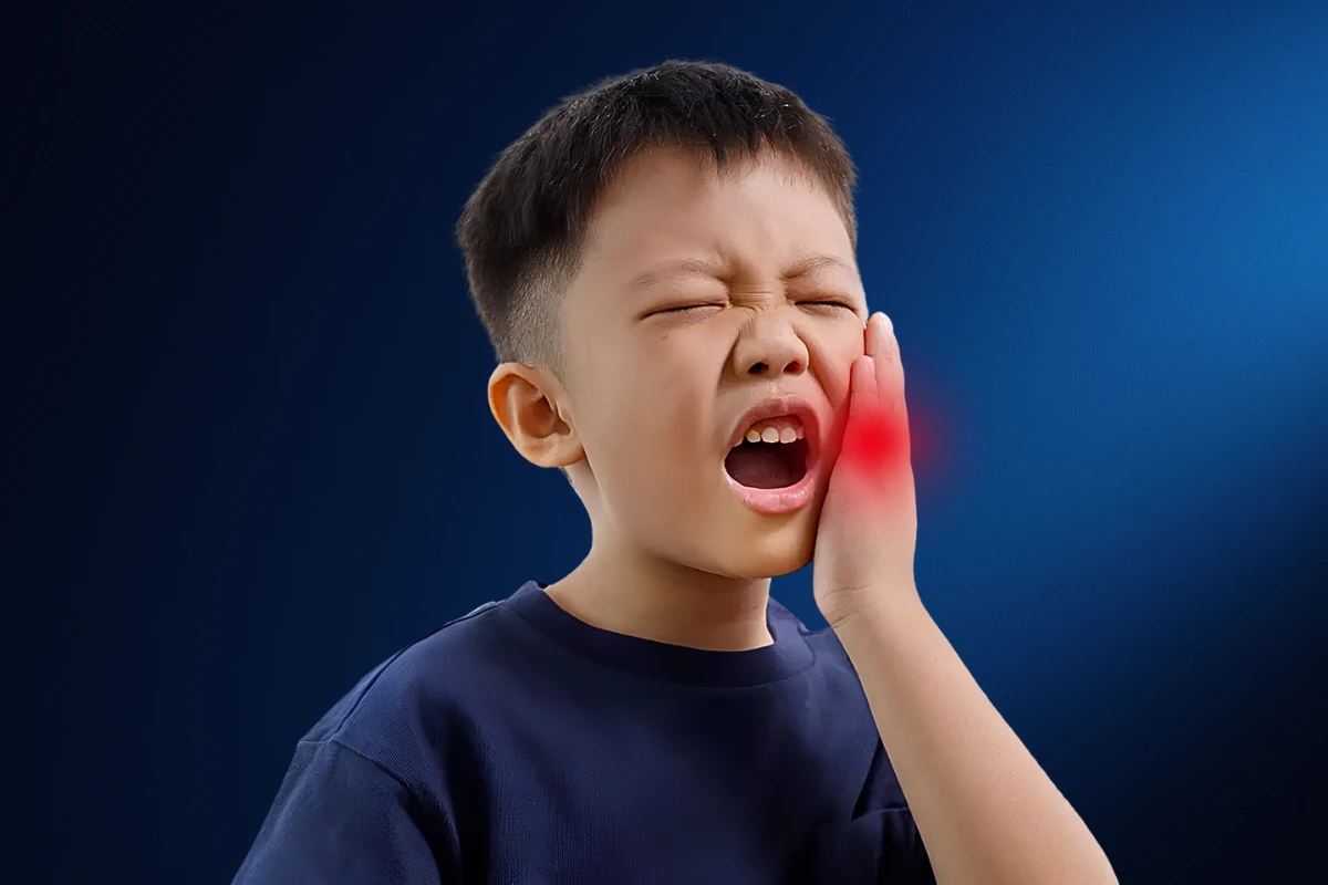 Child holding their cheek due to severe toothache, highlighting the need for prompt pediatric dental care.