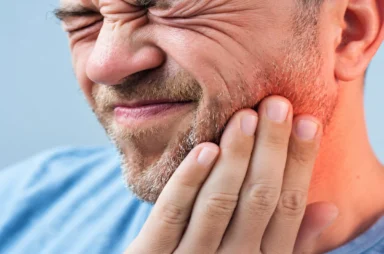 Man holding his face in discomfort due to jaw joint pain and muscle tension